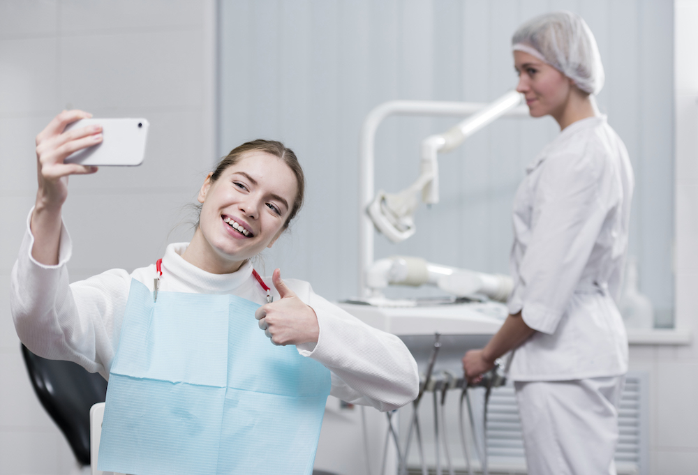 счастливый пациент делает селфи в кабинете стоматолога